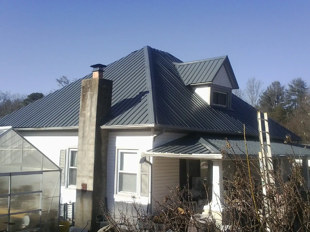 Dark blue standing seam metal roof on a white farmhouse with dormer — Slate & Tile Roof Repair by Roofing Brothers in Sharon