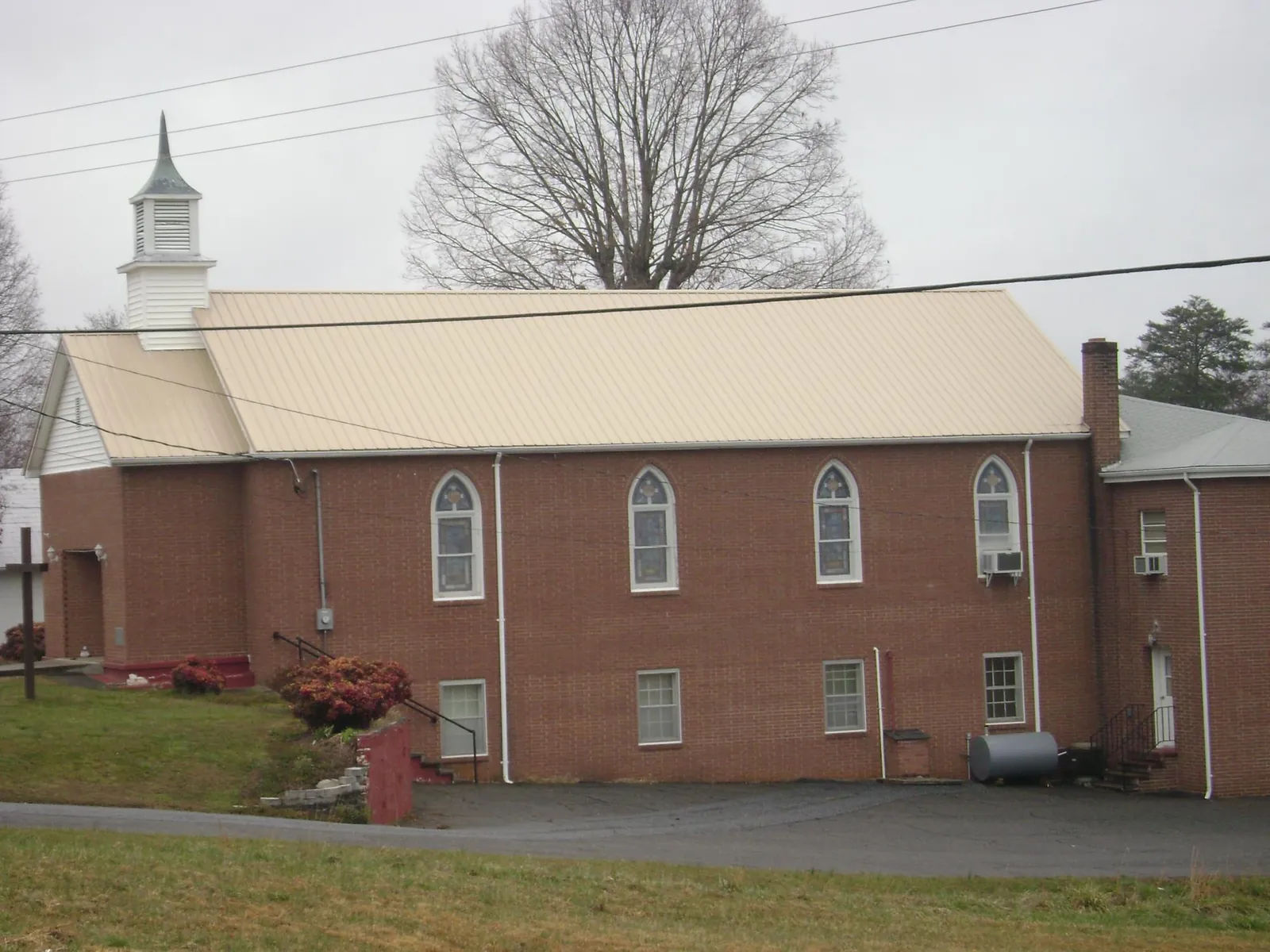 New tan metal roof on a brick church with a white steeple in Sharon